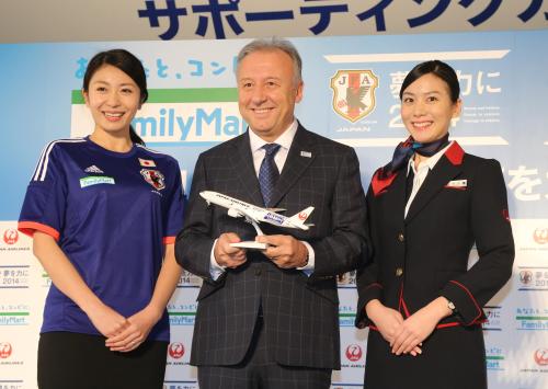 日本代表ユニホームを着たファミリーマート社員（左）と日本航空ＣＡ（右）に囲まれ笑顔のザッケローニ監督