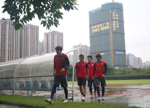 練習を終え、中国・広州の街並みを背に雨の中バスに向かう柿谷（左から２人目）と南野