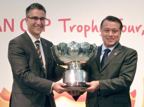 サッカー・アジア杯の優勝カップを手にする大会組織委のマーク・ファルボ最高執行責任者（左）と日本サッカー協会の田嶋幸三副会長
