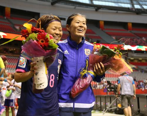 ＜女子Ｗ杯　日本・スイス＞試合後、１５０試合出場を達成した宮間（左）と２００試合出場達成の澤はファンから花束を渡され笑顔を見せる