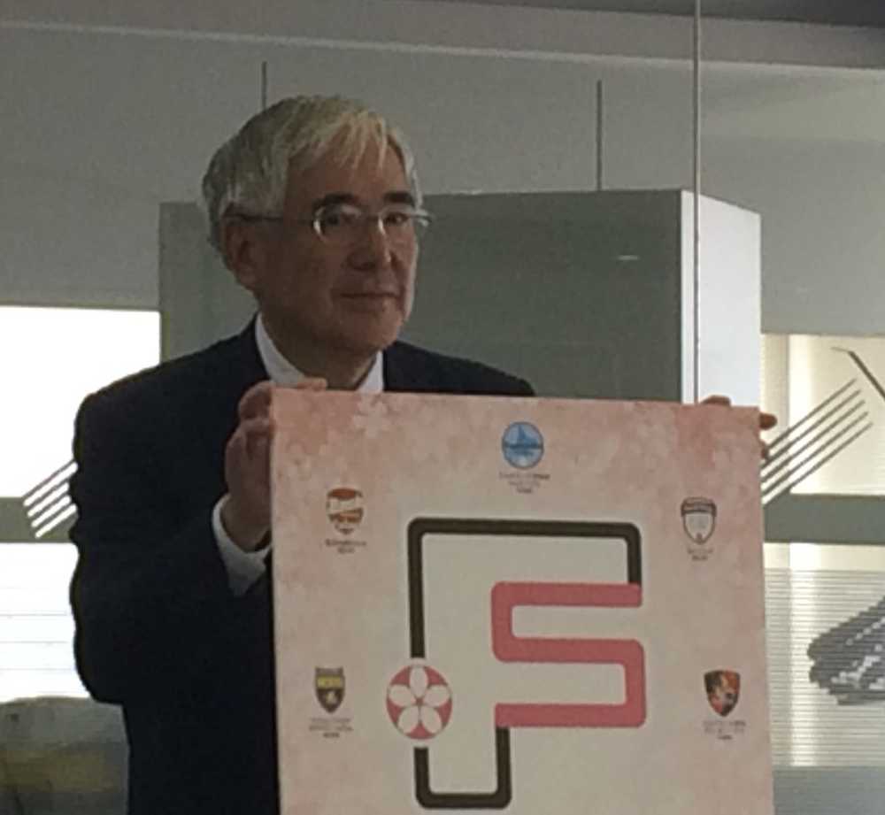 日本女子フットサルリーグの大会タイトルマークを掲げる小倉会長