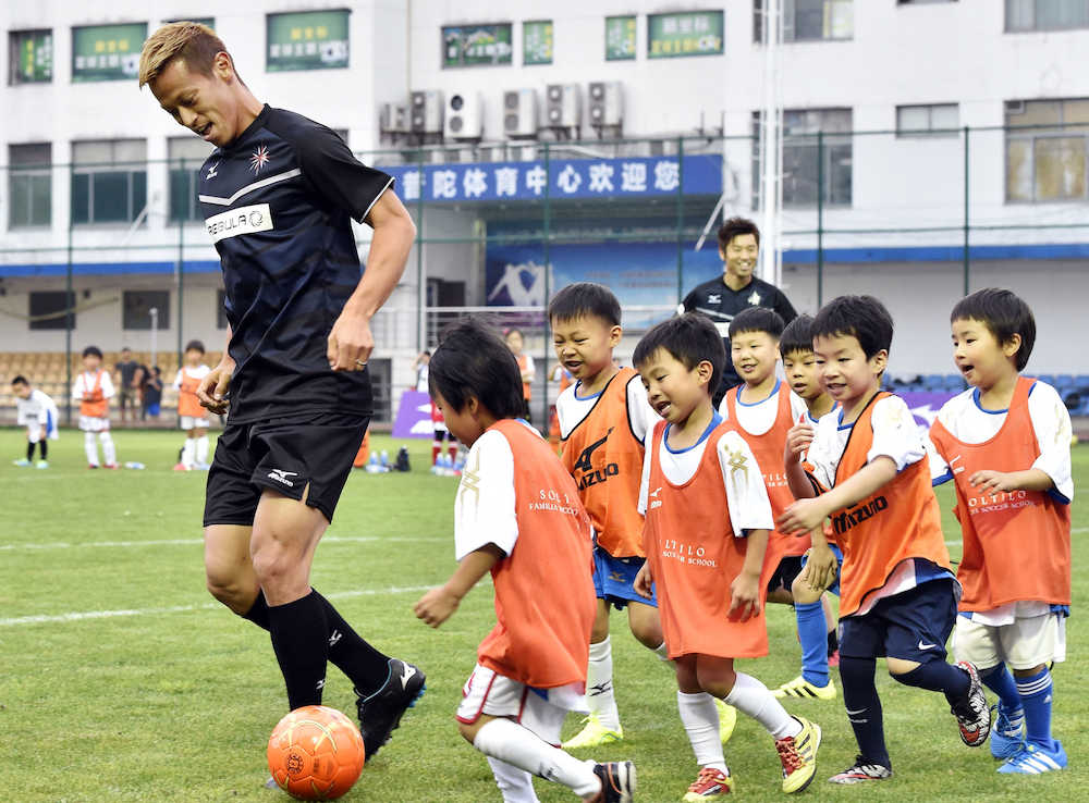 子どもたちとサッカーをする本田