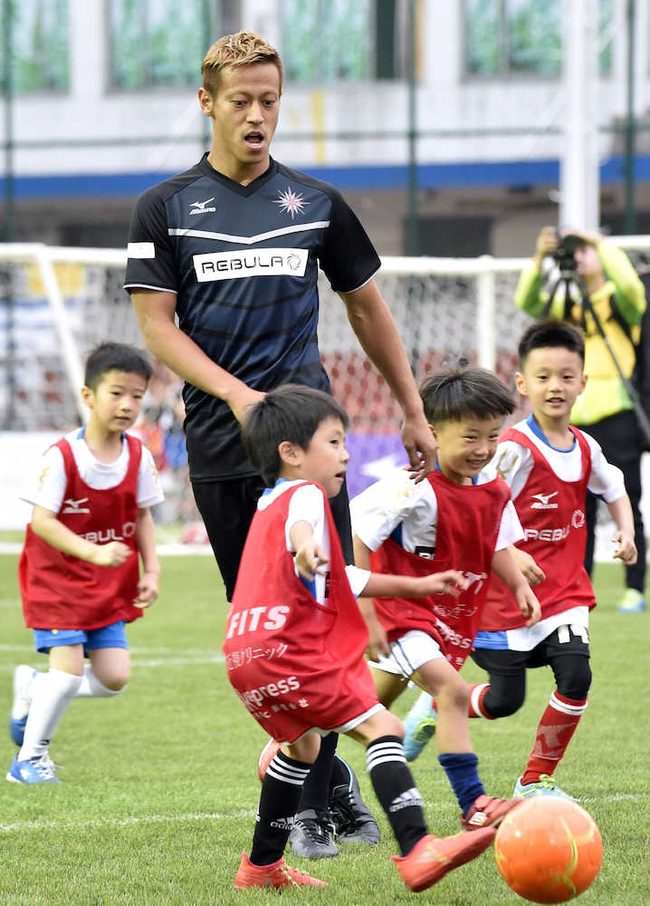子どもたちとサッカーをする本田
