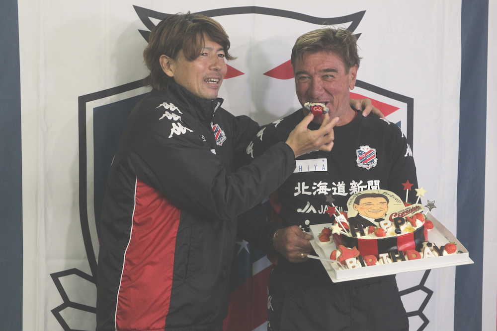 誕生ケーキに笑顔を見せる札幌・ペトロヴィッチ監督と杉浦コーチ兼通訳（左）