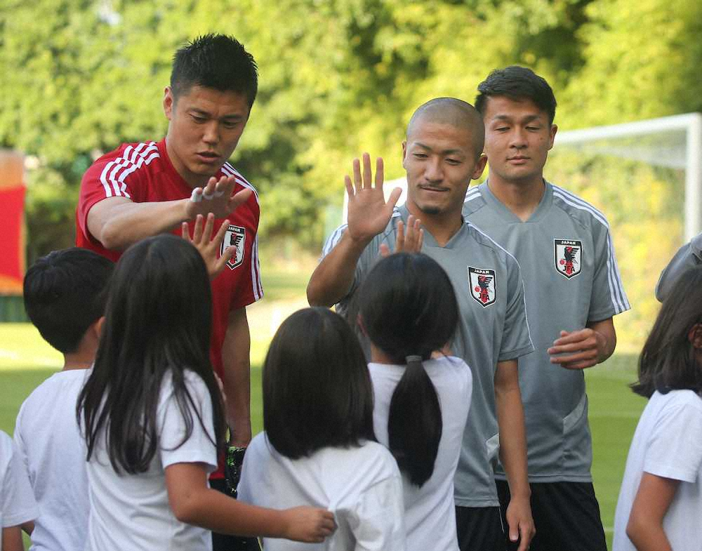 日本代表練習を見学に訪れた生徒らとタッチする川島（左）と前田（撮影・大塚　徹）