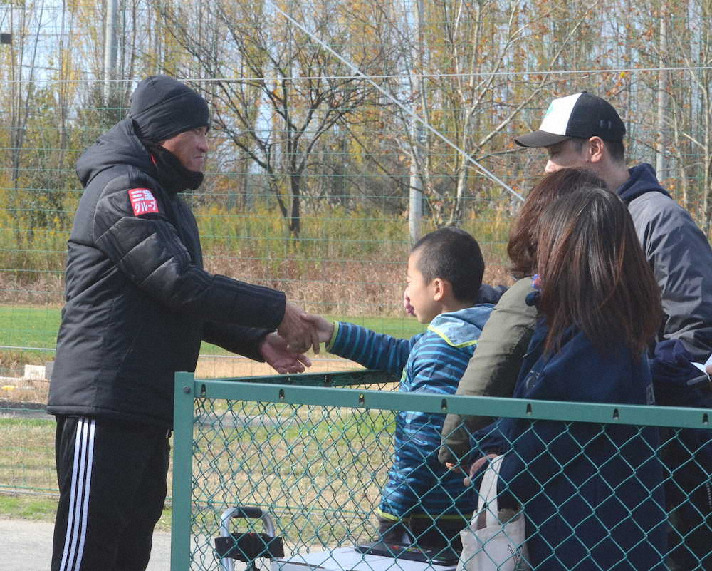 退任が発表され、サポーターと握手を交わすJ2新潟の吉永監督（左）