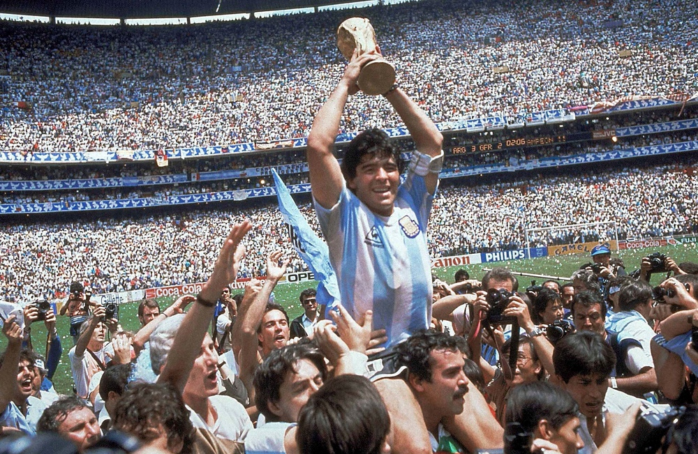 神の子天へ――。86年、W杯メキシコ大会で優勝し、チームメート担ぎ上げられ、ワールドカップを掲げるアルゼンチン代表のMFマラドーナ氏（中央）