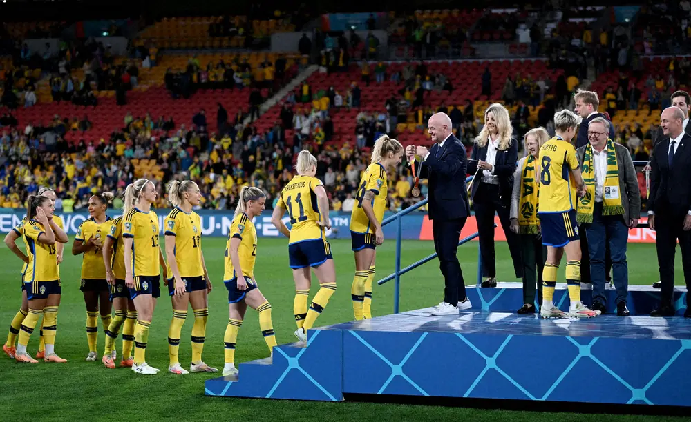 女子W杯3位になったスウェーデン代表イレブンに銅メダルをかけるFIFA・インファンティノ会長（中央右）（ロイター）