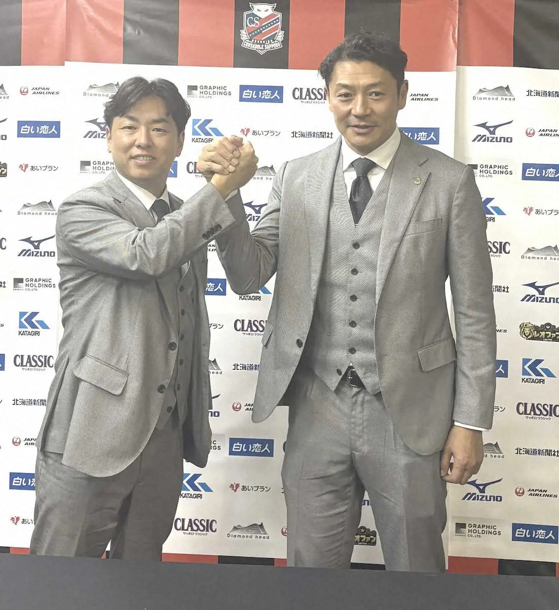 【画像・写真】ガッチリ握手をするコンサドーレ札幌の石水創代表取締役社長（左）と河合竜二GM