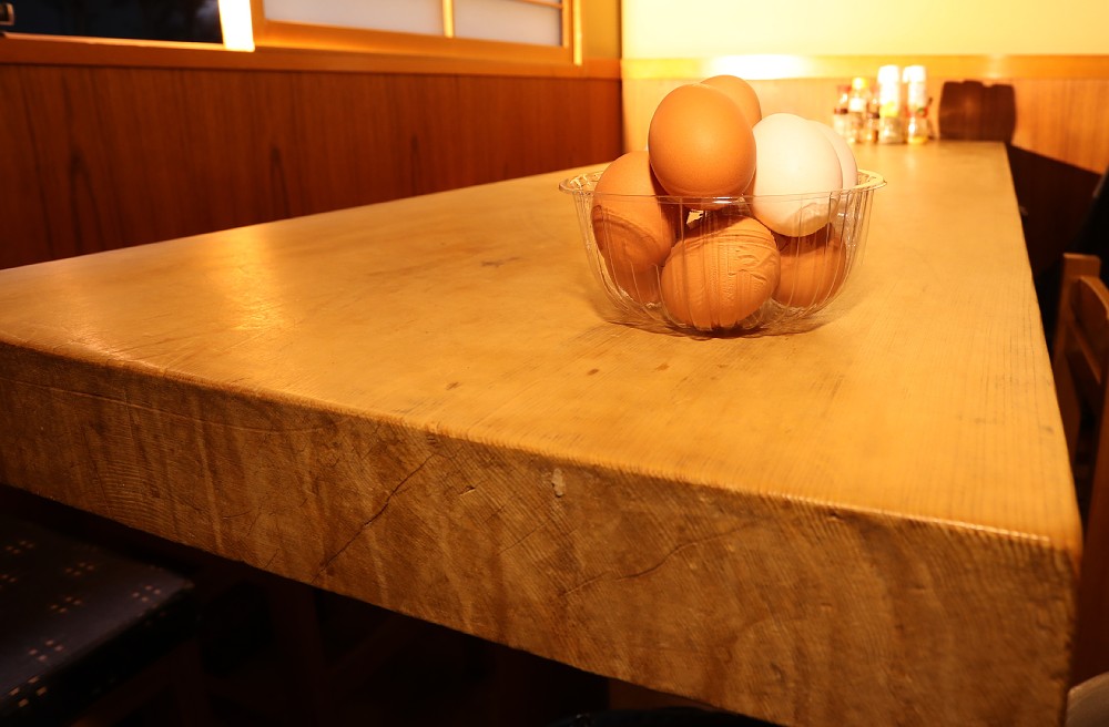 店自慢のひのき造りのテーブルにはサービスの生卵