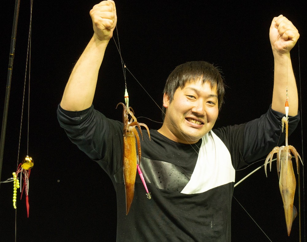 釣り上げたスルメイカを手に笑顔を見せる、この日のサオ頭・愛知県あま市の宮崎晃大さん