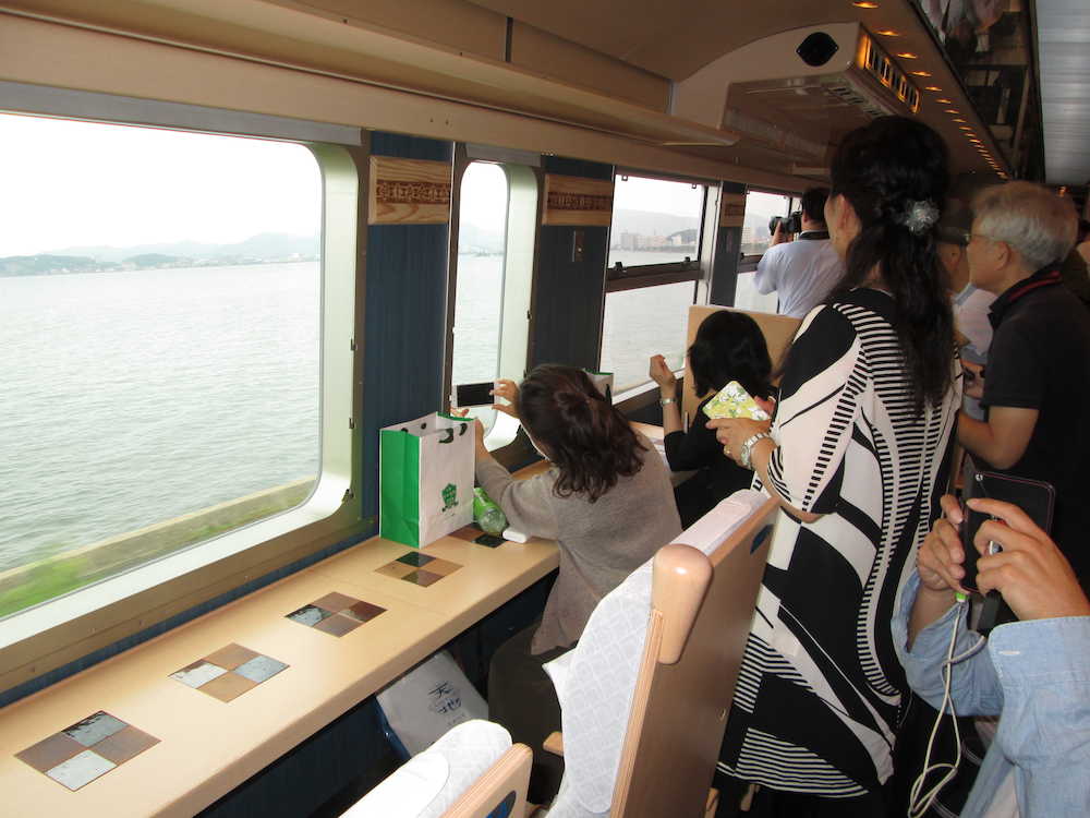 車窓を流れる日本海の絶景にシャッターチャンスを狙う乗客