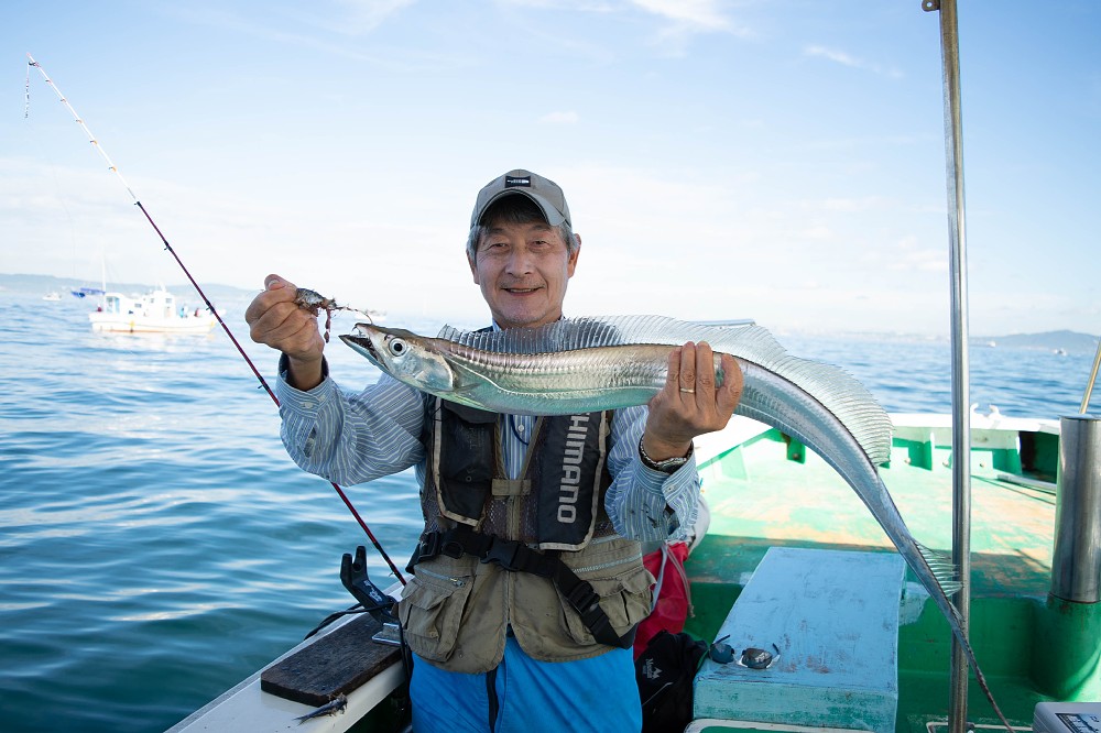 船内で最も大きい１０３センチのタチウオを釣り上げニッコリする神戸市の鈴木稔さん