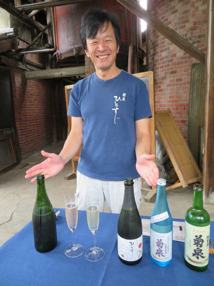 菊泉やスパークリング清酒などの銘酒を前に笑顔の滝澤酒造の社長、滝澤英之さん