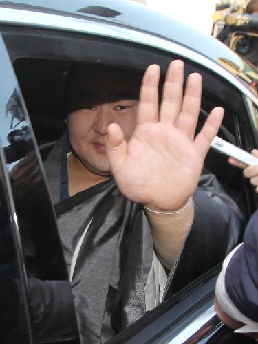 会見を終え、国技館を出る朝青龍は車を取り囲んだ報道陣に手を振ってみせる