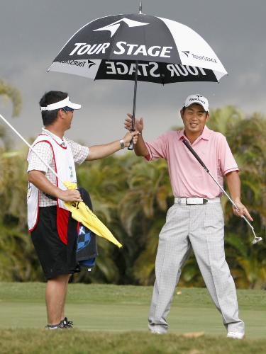第２ラウンド、１５番で突然の雨に、傘を手にする池田勇太（右）