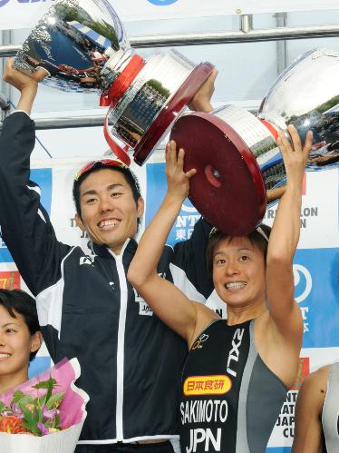 表彰台でカップを掲げて喜ぶ男子優勝の山本良介（左）と女子優勝の崎本智子