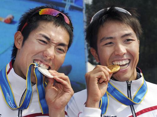 トライアスロン男子で獲得したメダルをかむ、優勝した細田雄一（右）と２位の山本良介