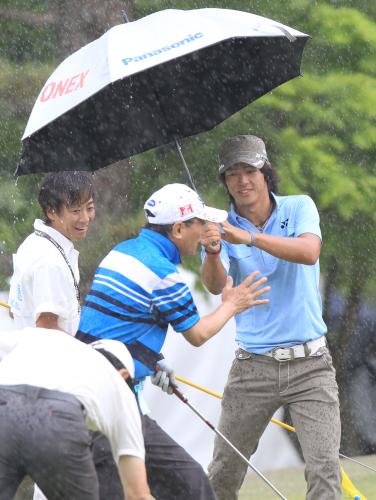 ＜中日クラウンズ＞プロアマ戦で突然降り出した強い雨の中、、同組のアマチュア選手らに傘を差し出す石川遼