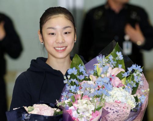 ２日、モスクワから韓国の仁川国際空港に到着し、花束を手に笑顔を見せるフィギュアスケートのキム・ヨナ