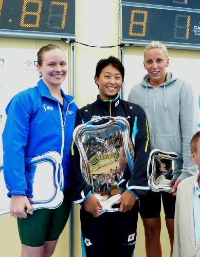 女子１００メートル平泳ぎを制し、表彰台で笑顔を見せる鈴木聡美（中央）