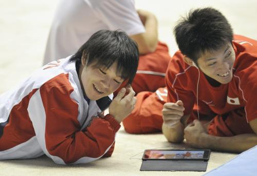 練習中、前日の競技の映像を確認し、笑顔を見せる内村航平（左）と田中和仁