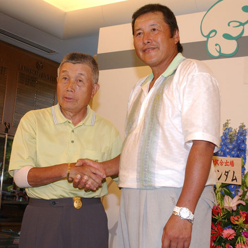 通算１０００試合出場達成のセレモニーを終え、杉原輝雄さん（左）と握手する尾崎将司