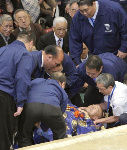 　把瑠都―若荒雄の一番で土俵下に落ち、担架で運び出される行司の木村庄三郎（中央下）