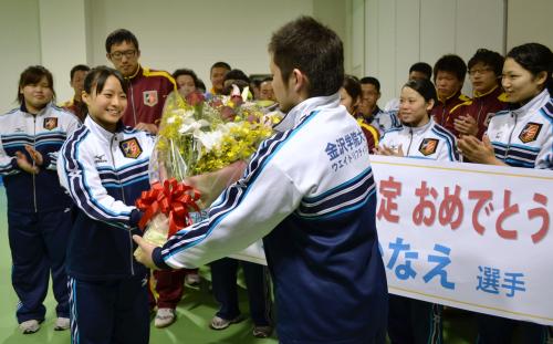 ウエイトリフティング部員の出迎えを受け、花束を手渡されるロンドン五輪の重量挙げ女子代表の八木かなえ（手前左）