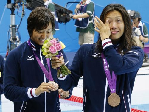女子４００メートルメドレーリレーで獲得した銅メダルを胸に涙をぬぐう寺川（右）と、メダルを見つめる鈴木