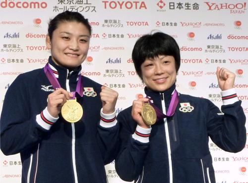記者会見し、レスリング女子で獲得した金メダルを手にガッツポーズする63キロ級の伊調馨選手（左）と48キロ級の小原日登美選手