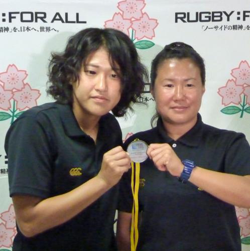 ラグビーＷ杯女子のアジア地区予選で獲得したメダルを掲げる中村知春主将（左）と浅見敬子ヘッドコーチ