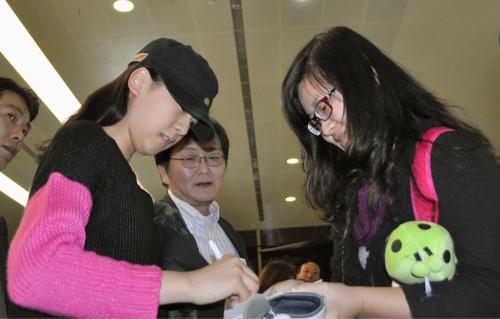 フィギュアスケートの中国杯で上海入りし、ファンの求めに応じてサインする浅田真央（左）