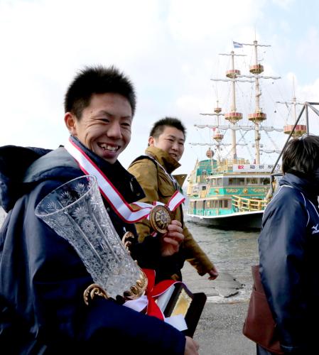 芦ノ湖の遊覧船の前でメダルを手に笑顔を見せる５区を走った服部