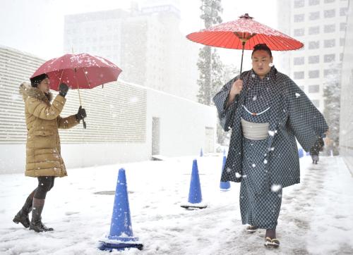東京に降る初雪の中で初場所２日目を迎え、場所入りする力士と、出迎えるファン