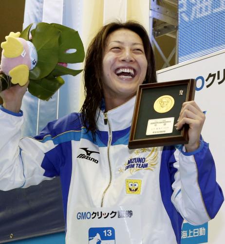 女子１００メートル背泳ぎで優勝し、表彰台で笑顔を見せる寺川綾