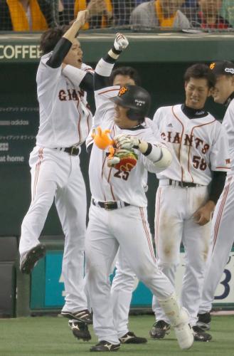 ６回に本塁打を放ち、坂本（左）らナインに迎えられる巨人・村田