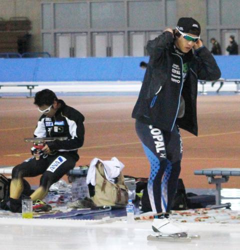 滑走する長島圭一郎（右）と、スケート靴を調整する加藤条治