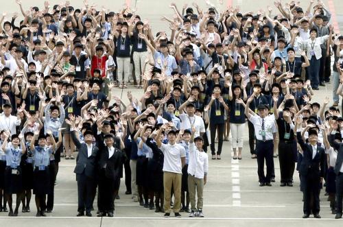 羽田空港で行われた２０２０年夏季五輪の招致イベントで、人文字作りに参加し手を振る人たち。前列中央は男子背泳ぎの入江、その右は体操男子の白井