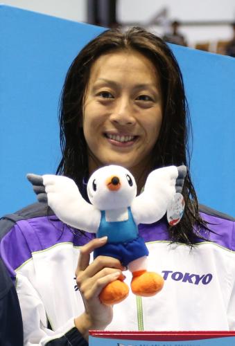成年女子１００メートル背泳ぎを制し、表彰台で笑顔を見せる寺川