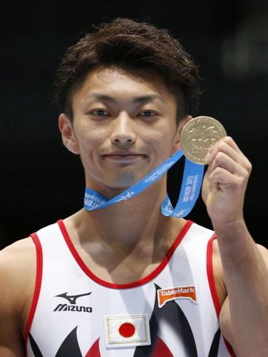 体操の世界選手権男子種目別のあん馬で獲得した金メダルを掲げる亀山耕平