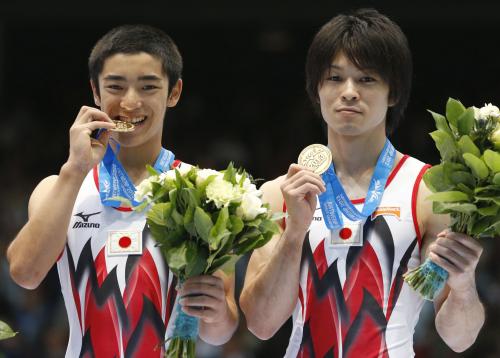 体操の世界選手権男子種目別の床運動で優勝し、金メダルをかじる白井健三。右は銅メダルの内村航平