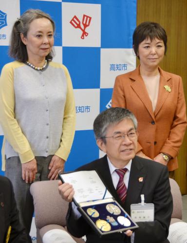 寄贈されたメダルを持つ岡崎誠也高知市長（下）。左は故北村久寿雄さんの長女真知子さん、右は次女皆川久仁子さん
