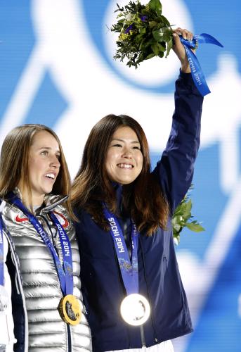 フリースタイルスキー女子ハーフパイプの銅メダルを胸に、笑顔で花束を掲げる小野塚彩那。左は金のマディー・ボーマン