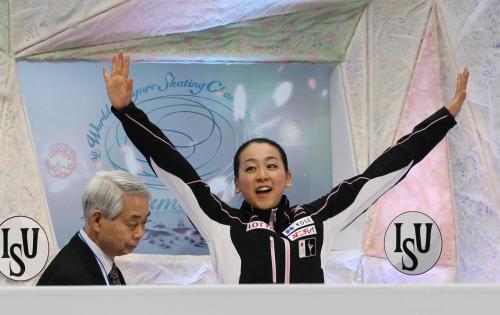 ＜フィギュア世界選手権女子ＳＰ＞滑り終えた浅田真央（右）はキスアンドクライで両手を大きく広げる。左は佐藤コーチ