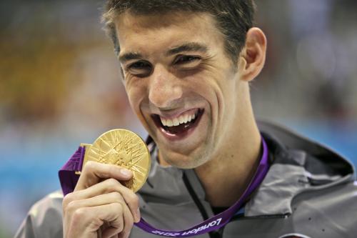 ロンドン五輪の競泳男子１００メートルバタフライで獲得した金メダルを手に笑顔のマイケル・フェルプス