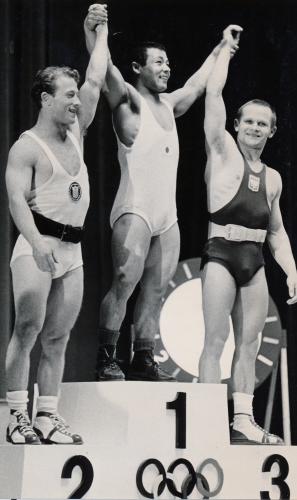 １９６４年東京五輪、ウエートリフティングフェザー級で金メダルを獲得し表彰台で笑顔の三宅義信氏（中）（左は銀メダルのバーガー、右は銅メダルのノバック）