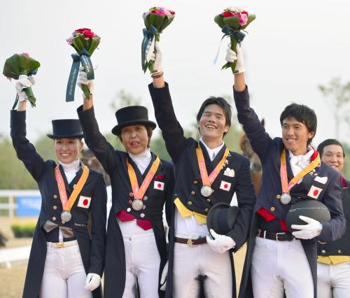 表彰式で花束を掲げる（左から）奥西、中村、佐渡、林