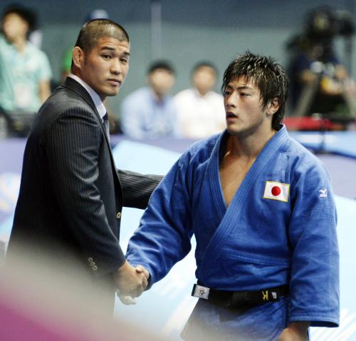 男子90キロ級で優勝し、柔道男子日本代表の井上康生監督（左）と握手を交わす吉田優也