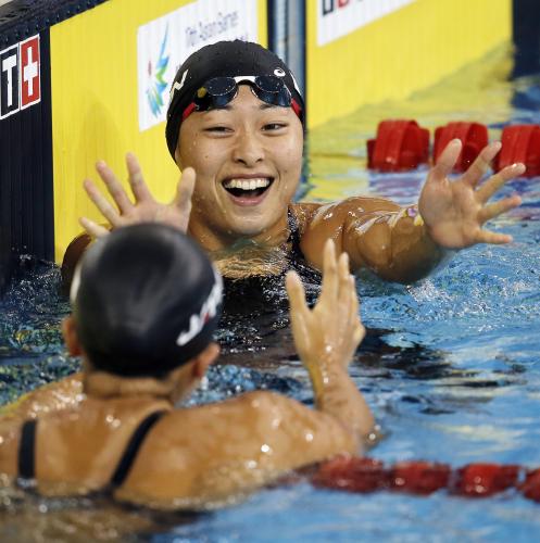 競泳女子50メートル平泳ぎで優勝し、４位の渡部香生子（手前）から祝福を受ける鈴木聡美